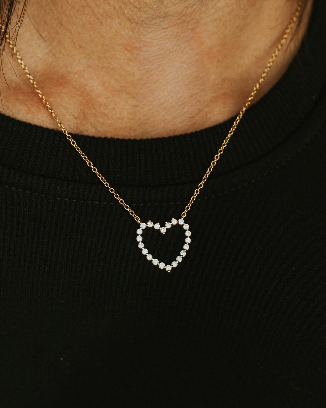 Jessica Signature Heart Pendant Necklace in gold with sparkling stones, worn with a black top